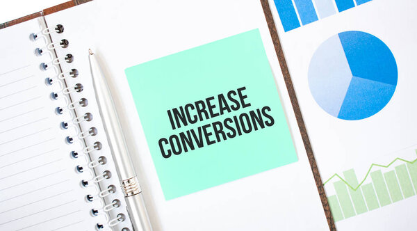 Green card on the white notepad. Text increase conversions. Business concept