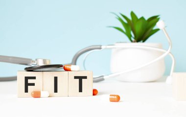 FIT kelimesi ahşap bir arka planda steteskopun yanındaki tahta küplere yazılmıştır. Tıbbi konsept
