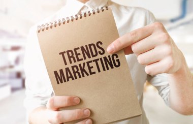 Yazı trendleri, iş adamlarının elindeki kahverengi kağıt not defterine pazarlama yapıyor. İş konsepti