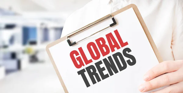 Text global trends on white paper plate in businessman hands in office. Business concept