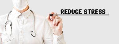 Doktor keçeli kalemle, tıbbi konseptle kelime REDUCE STRESS yazıyor.