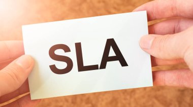 Bir iş adamının elindeki beyaz kart kağıdına yazılmış SLA sözcüğü. Özet konsepti. kırmızı ve beyaz kağıt