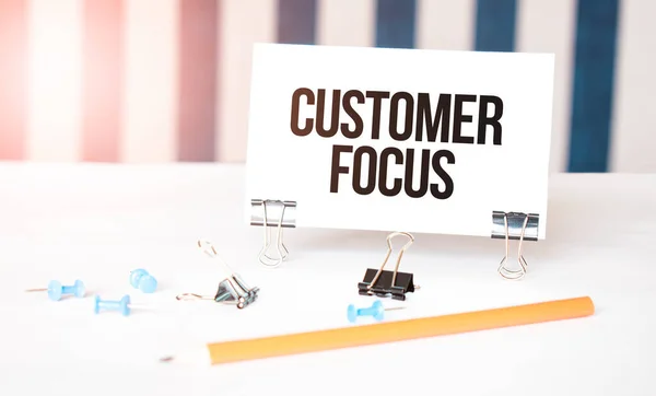 Customer focus sign on paper on white desk with office tools. Blue and white background