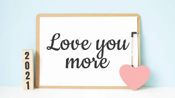 爱你更多的文字和2021立方体与红心形装饰蓝色木制桌子的背景 快乐情人节的理念 — 图库照片