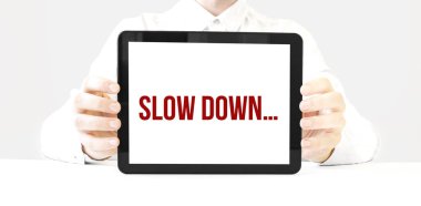 Text SLOW DOWN on tablet display in businessman hands on the white bakcground. Business concept clipart