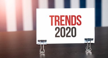 TRENDS 2020, gün ışığında karanlık masanın üzerindeki kağıda imza atın. Mavi ve beyaz arkaplan