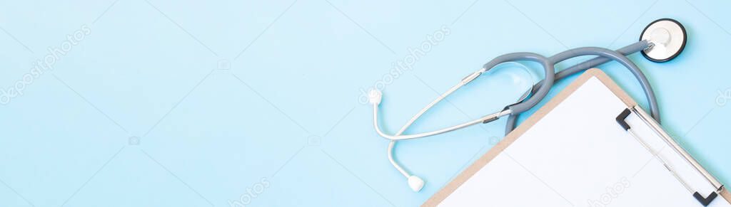 A wooden clipboard and stethoscope with white paper on it, set against a blue background