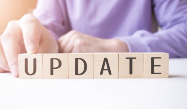 İş adamı, masa arkasında UPDATE iş sözcüğüyle tahta küp bloğu tutuyor. Görev, Vizyon ve temel değerler kavramı