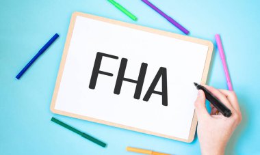 Renkli keçeli kalemlerle çevrili bir defterde FHA metni, iş konsepti fikri,