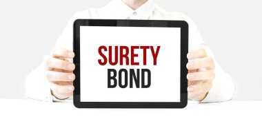Text surety bond on tablet display in businessman hands on the white bakcground. Business concept clipart