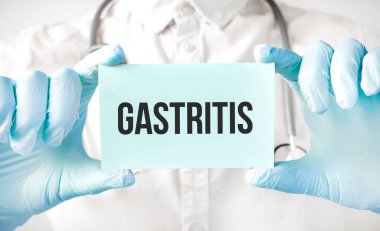 Doktor elinde kart tutuyor ve GASTRITIS kelimesini işaret ediyor.