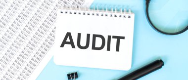 Mali belgelerde beyaz not defteri ve büyüteç. AUDIT 'ye mesaj at. İş konsepti