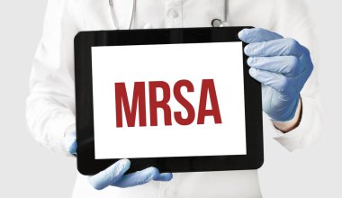 Doktorun elinde MRSA yazılı bir tablet var.