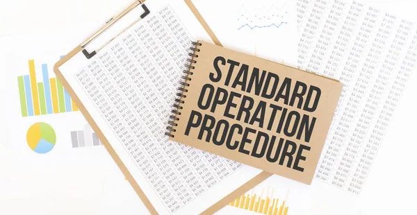 Text Standard Operation Procedure on brown paper notepad on the table with diagram. Business concept