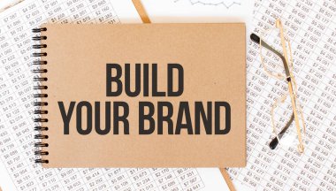 Markanızı İnşa Edin yazan renkli not defteri. Gözlüklü ve metin belgeli not defteri. İş konsepti