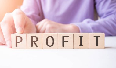 İş adamı, masa arkasında PROFIT iş sözcüğüyle tahta küp bloğu tutuyor. Görev, Vizyon ve temel değerler kavramı