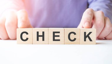 İş adamı, masa arkasında CHECK iş sözcüğüyle tahta küp bloğu tutuyor. Görev, Vizyon ve temel değerler kavramı