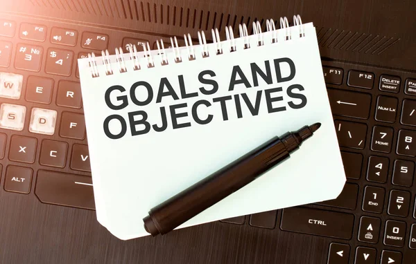 White paper sheet with text Goals and Objectives on the black laptop