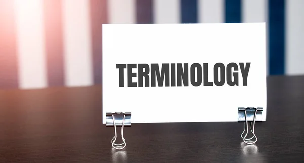 Terminology sign on paper on dark desk in sunlight. Blue and white background