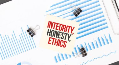Sarı yapışkan notlar, beyaz ofis masasının üzerinde INTEGRITY, HONESTY, ETHICS yazılı. İş konsepti.