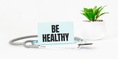 Sağlıklı ol, not defteri, steteskop ve yeşil bitki.