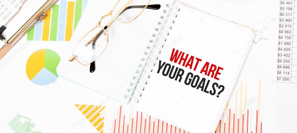 Texto Cuáles son sus metas en bloc de notas blanco, gafas, gráficos y ...