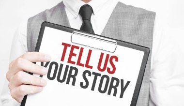 Bize hikayenizi gri arka plandaki bir iş adamının elindeki deftere yazın. Bir adam parmağıyla metni işaret ediyor.