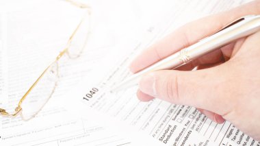 Erkek eli kalem tutuyor ve vergi formunu işaret ediyor..