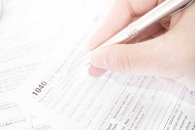 Erkek eli kalem tutuyor ve vergi formunu işaret ediyor..