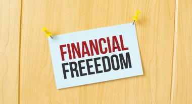 Ahşap duvara yapıştırılmış yapışkan bir nota yazılmış FİNANSIL ÖZGÜRLÜK tabelası