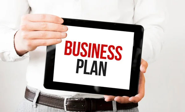 Text business plan on tablet display in businessman hands on the white bakcground. Business concept