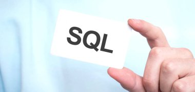 Mavi kazaklı adam elinde SQL yazılı bir kart tutuyor, iş konsepti.
