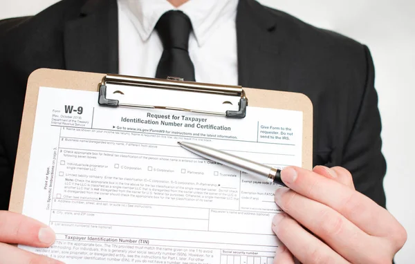 Man holding US tax form W-9. Tax form law document irs business concept