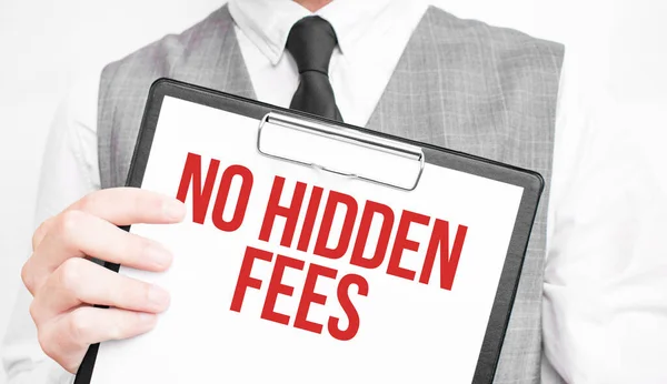 NO HIDDEN FEES inscription on a notebook in the hands of a businessman on a gray background, a man points with a finger to the text