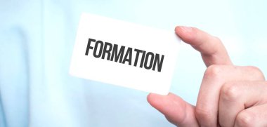 Mavi kazaklı bir adam elinde metin formasyonu, iş konsepti olan bir kart tutuyor.