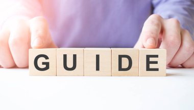 İş adamı, masa arkasında rehber iş sözcüğüyle tahta küp bloğu tutuyor. Görev, Vizyon ve temel değerler kavramı