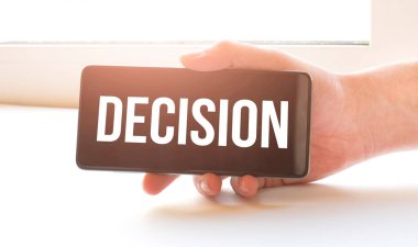 Adam evde kilit altında oturuyor ve elinde imzalı siyah bir telefon tutuyor.