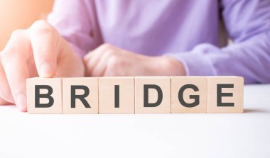 İş adamı, masa arkasında BridGE iş sözcüğüyle tahta küp bloğu tutuyor. Görev, Vizyon ve temel değerler kavramı