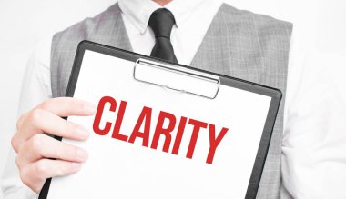 Gri arkaplanlı bir iş adamının elindeki bir defterde bariz bir yazı var. Bir adam parmağıyla metni işaret ediyor.