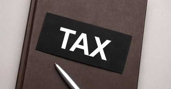 Tax sign written on the black sticker on the brown notepad. Tax concept