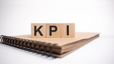 Tahta küplere KPI 'yi ve beyaz arkaplanda renkli not defterini yaz