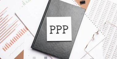 PPP 'yi ofis araçlarıyla birlikte not defterine, kalemi de mali rapora yaz. İş ve mali konzept. Hesap makinesi ve diyagramı olan çalışma kağıdı.