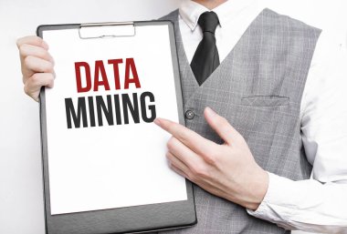 Gri arkaplanlı bir iş adamının elindeki bir defterde DATA Madencilik yazılıydı.