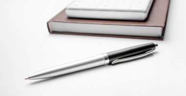 Beyaz arkaplanda hesap makinesi kalem ve defter