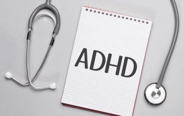 Bej bir arka planda, steteskop ve üzerinde ADHD tıp konsepti yazan beyaz bir not defteri var.