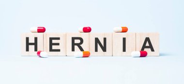 Fıtık. Tahta küplerdeki kelime. Küpler yansıtıcı beyaz bir yüzey üzerinde duruyor. Tıp konsepti