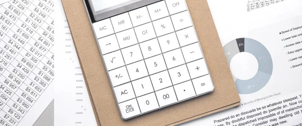 Calculator and an empty Notepad page on the office Desk with financial indicators and charts. Top view with a copy of the text input space.