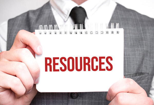 Бизнесмен с блокнотом с текстом RESOURCES. Концепция бизнеса