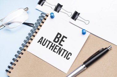 Ofis masasında, gözlüklü, not defterli ve raptiyeli bir not defteri..