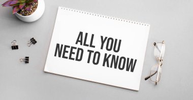 Bilmen gereken tek şey beyaz bir defterde, siyah çerçeveli bir gözlük ve yeşil bir bitkinin yanında yazılı..